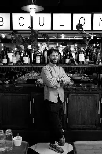 Le chef Julien Duboué debout sur le bar, sous les lettres BOULOM